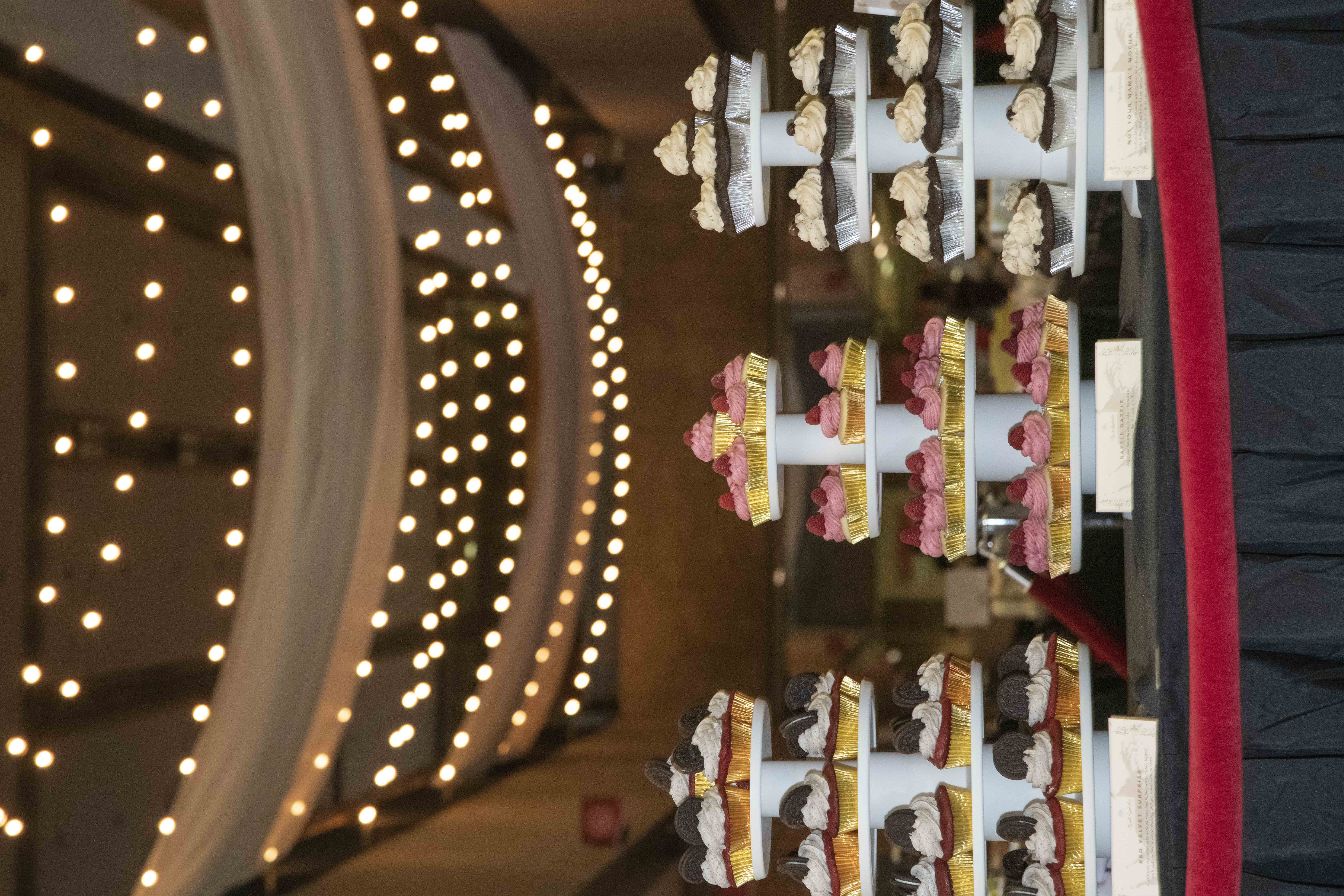 Three four-tiered cupcake stands are on display at a table.