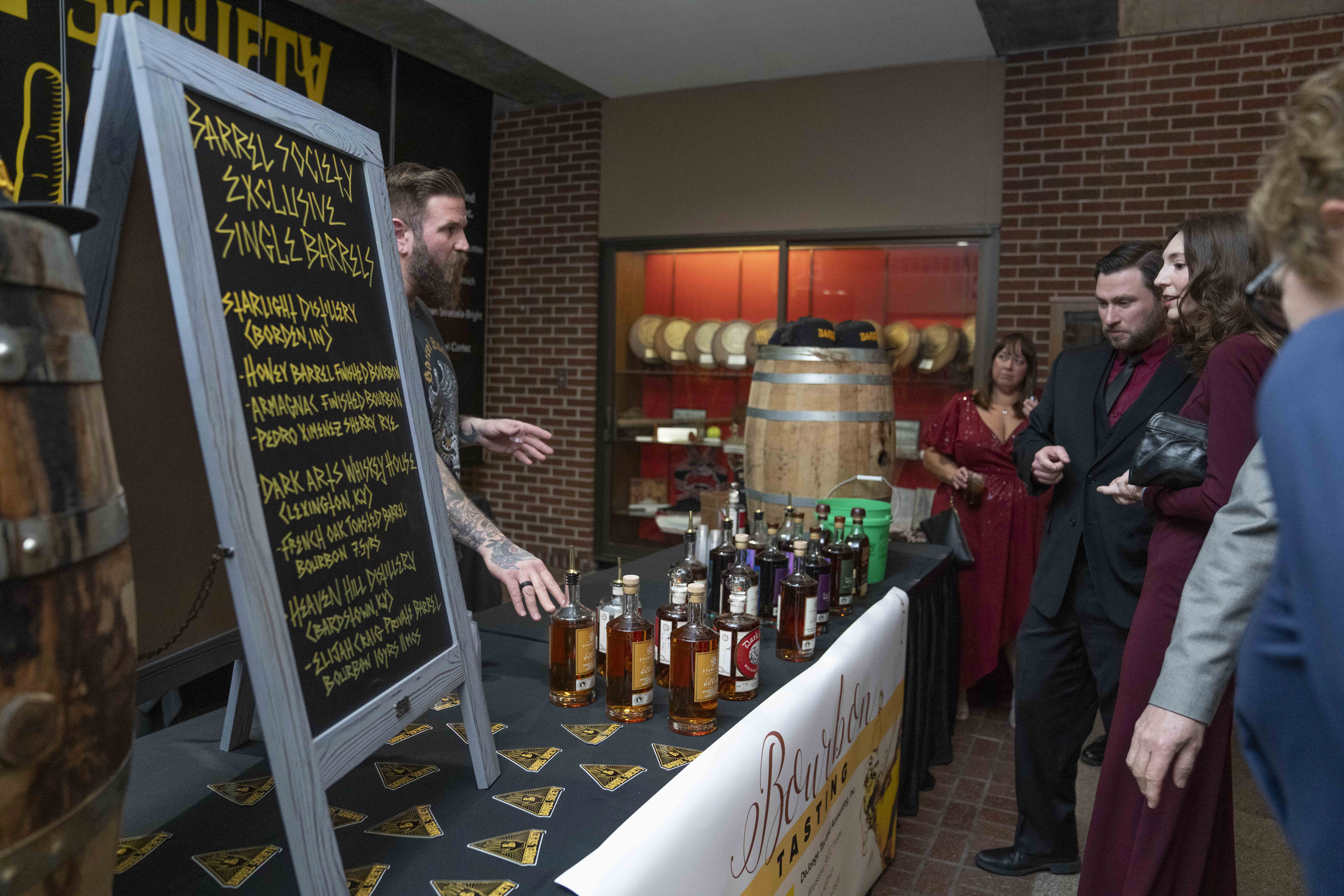A man describes bourbon selection to Chocolate Rendezvous guests at the Bourbon Tasting table.