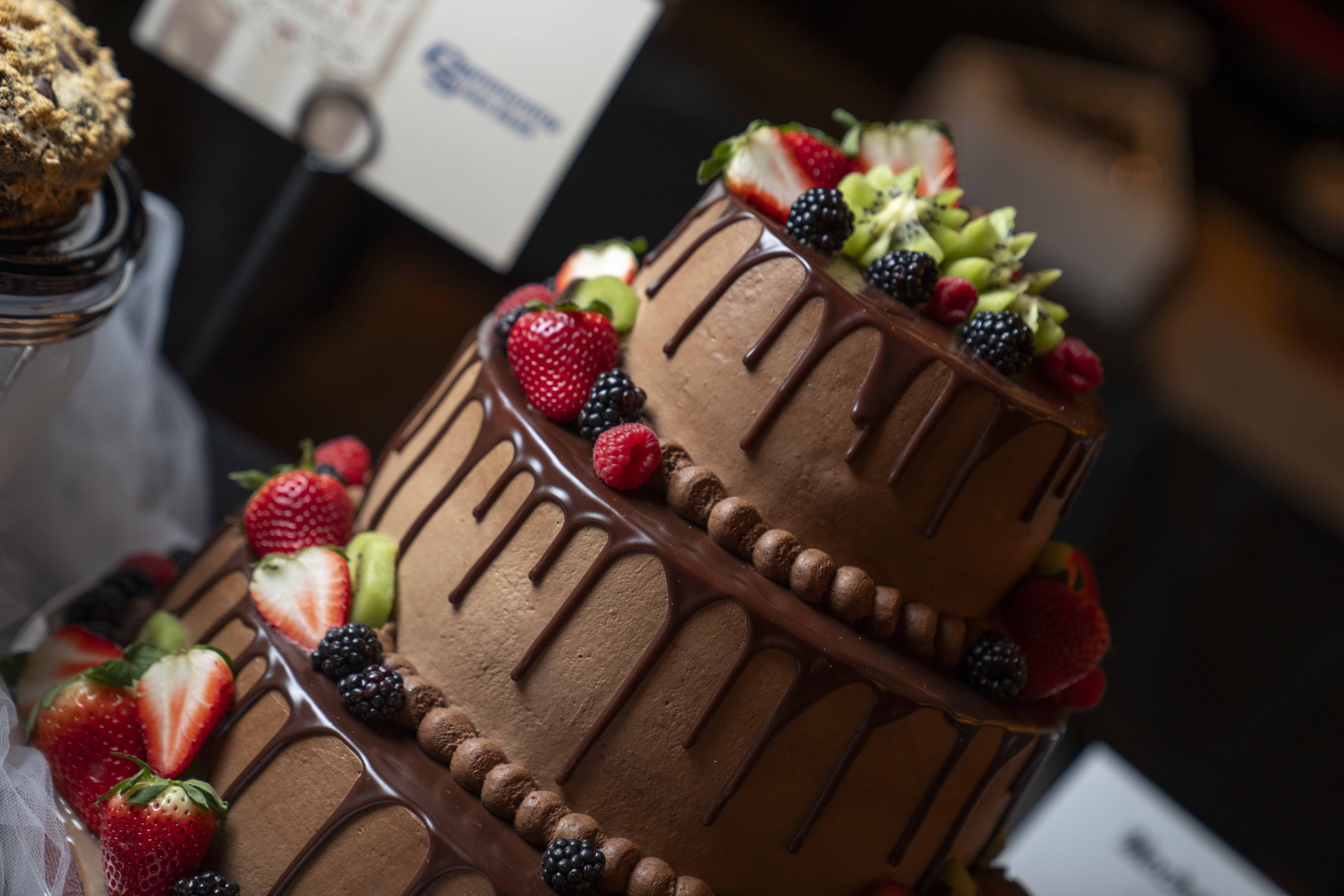 Close-up of a three-tiered chocolate cake with chocolate drip and berry detailing.